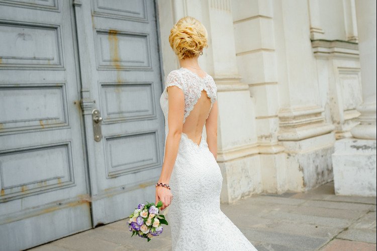Bride wearing a lace wedding gown with an elegant open-back design, showcasing modern bridal gown trends.